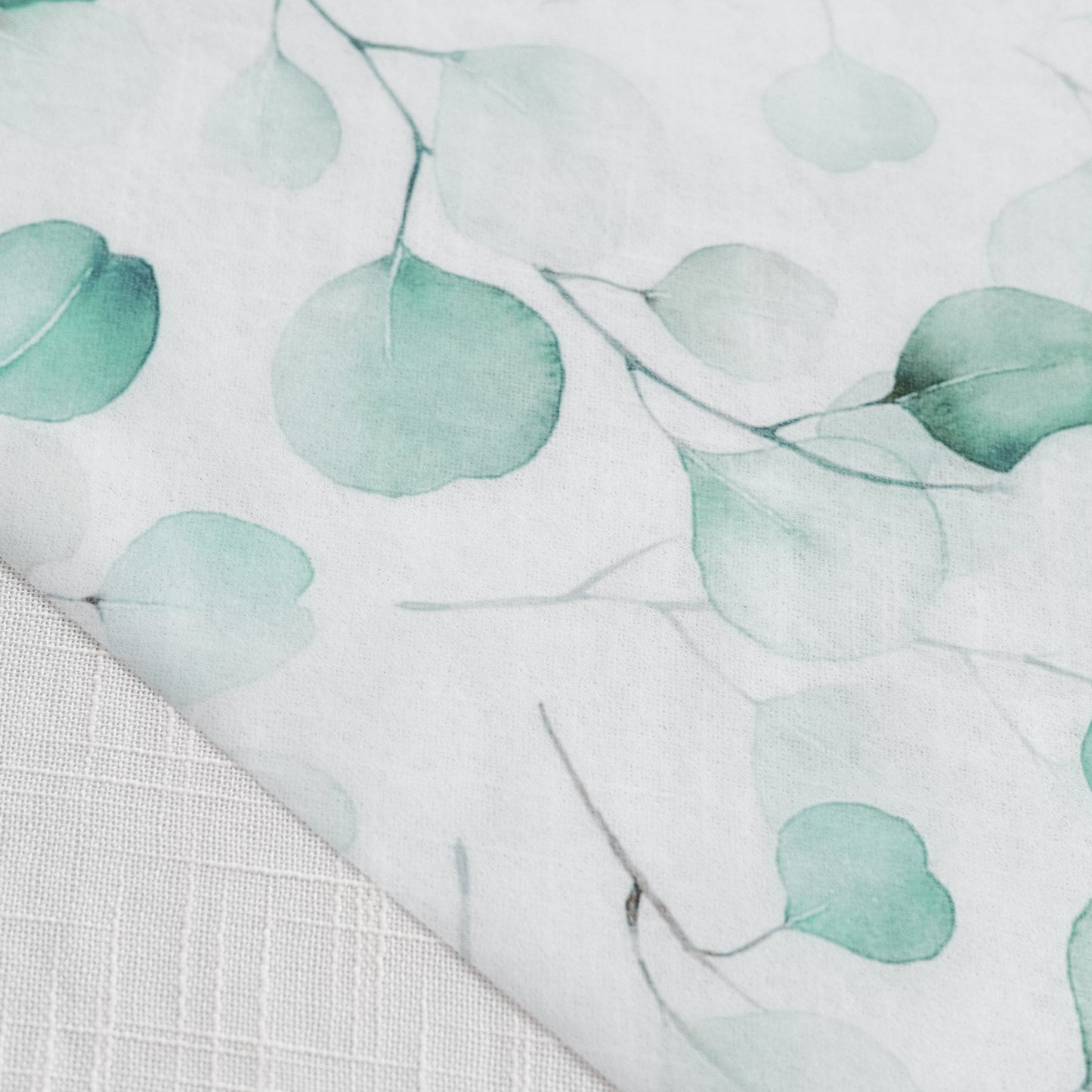 White table runner with green eucalyptus leaves print.