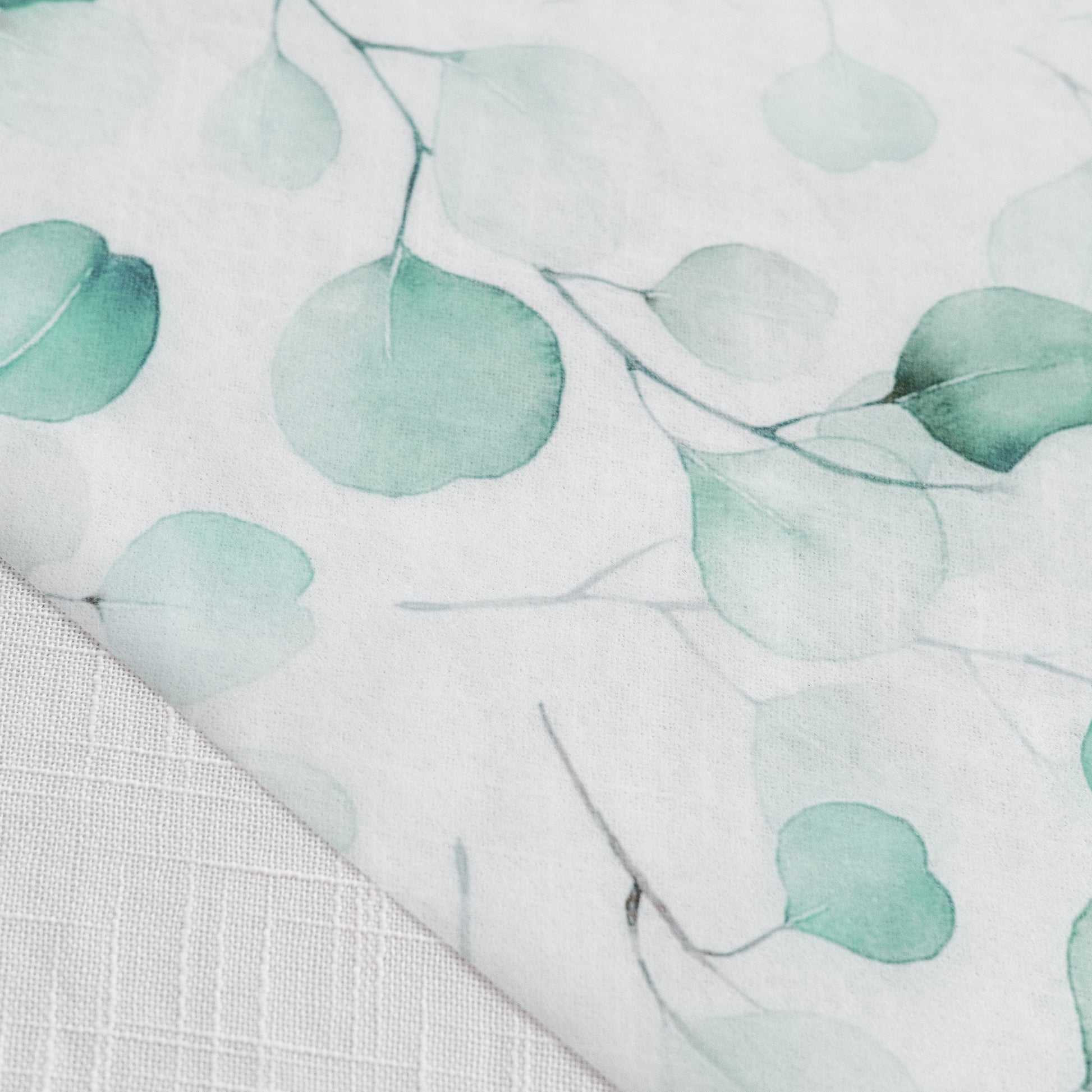 White table runner with green eucalyptus leaves print.