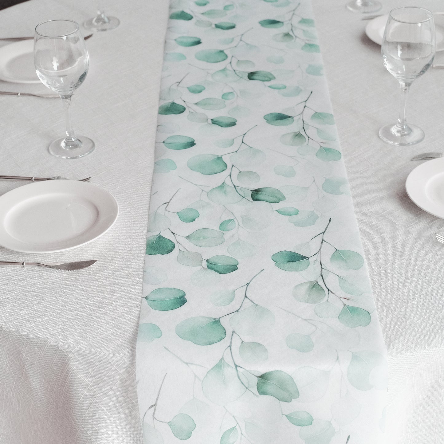 White table runner with green eucalyptus leaves print for stylish dining decor.