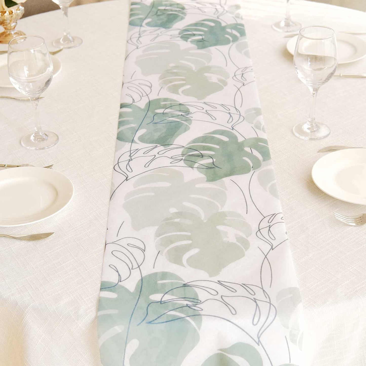 White table runner with green monstera palm leaves print.