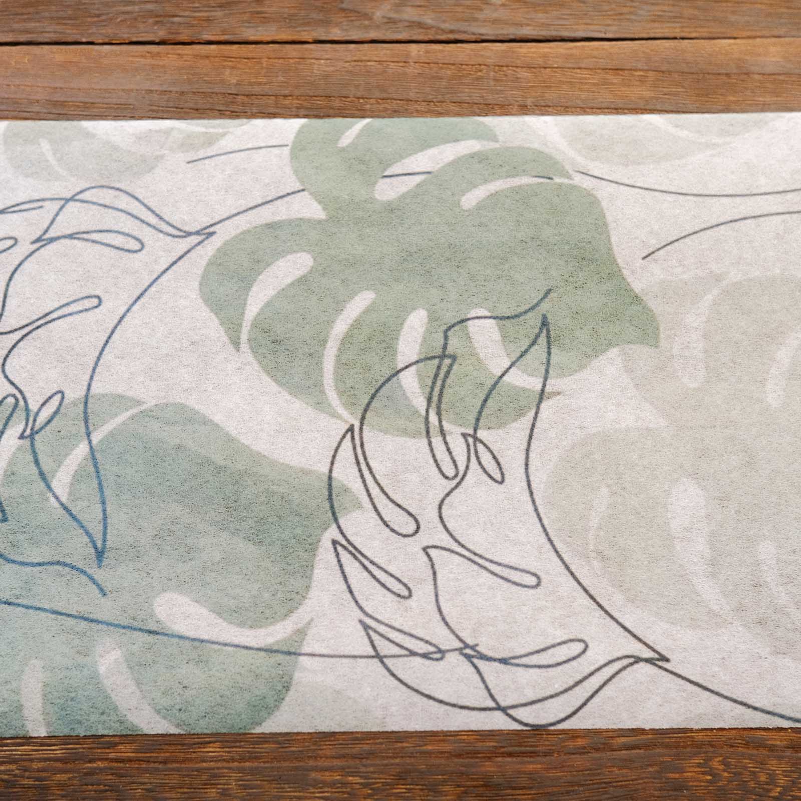 White table runner with green monstera palm leaves print for dining decor.