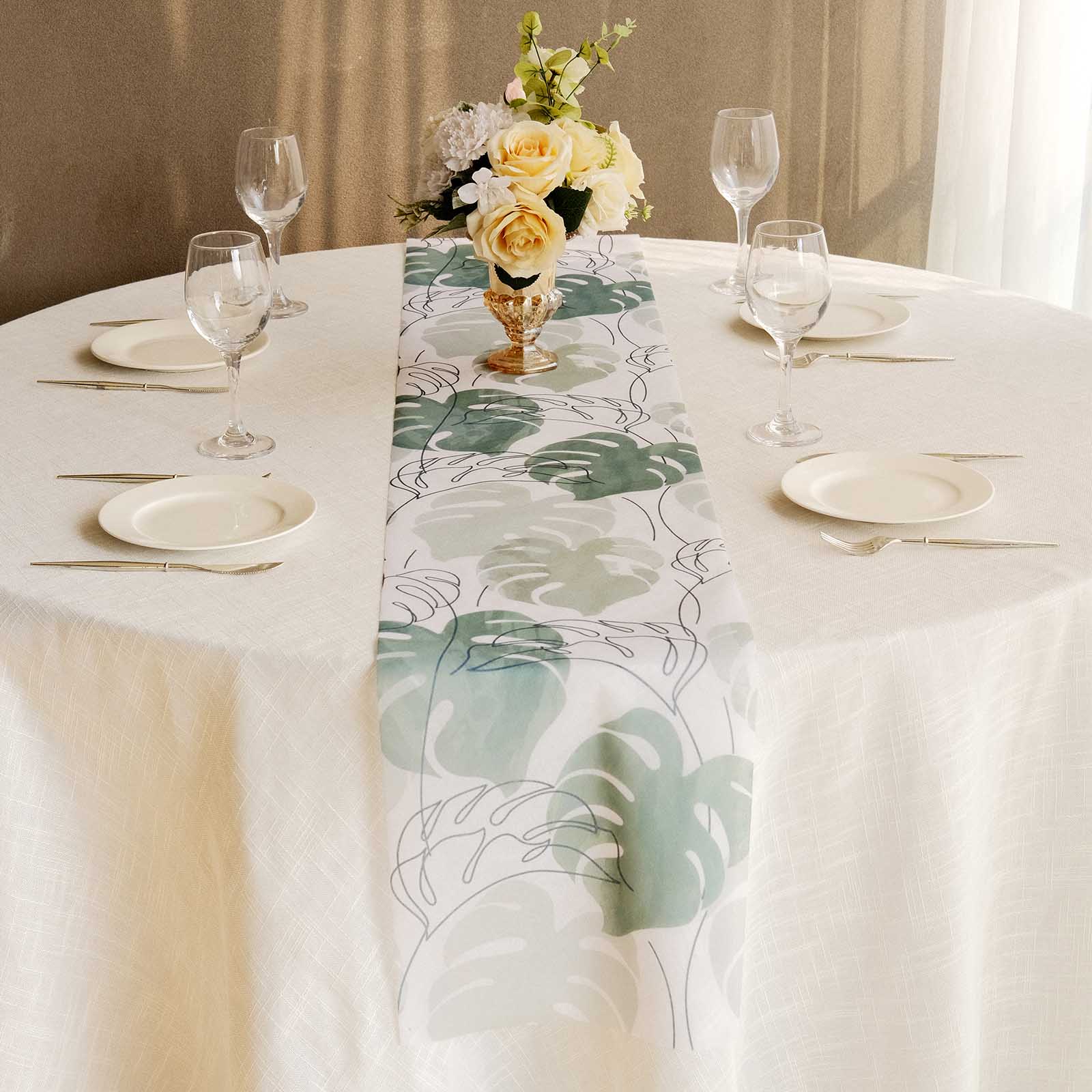 White table runner with green monstera palm leaves print on a dining table.