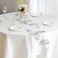 White table runner with green olive leaves print on a dining table.