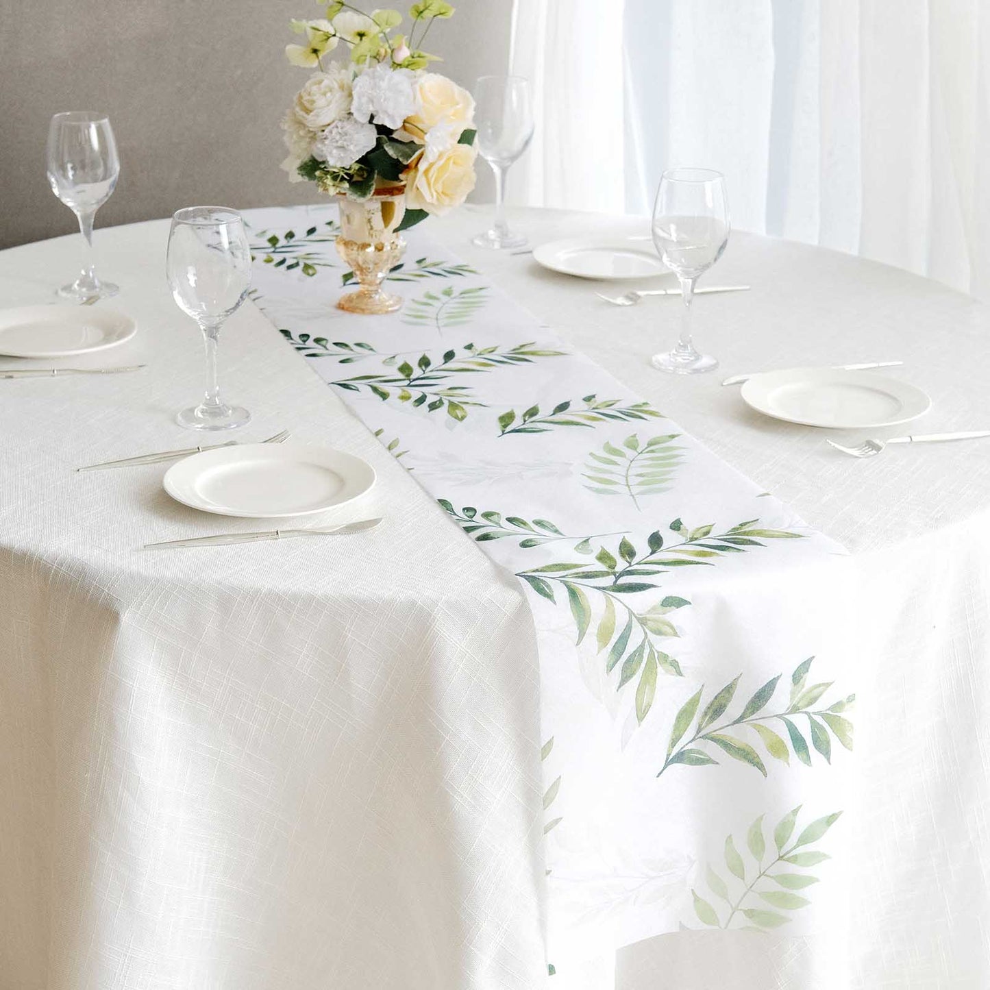 White table runner with green olive leaves print on a dining table.