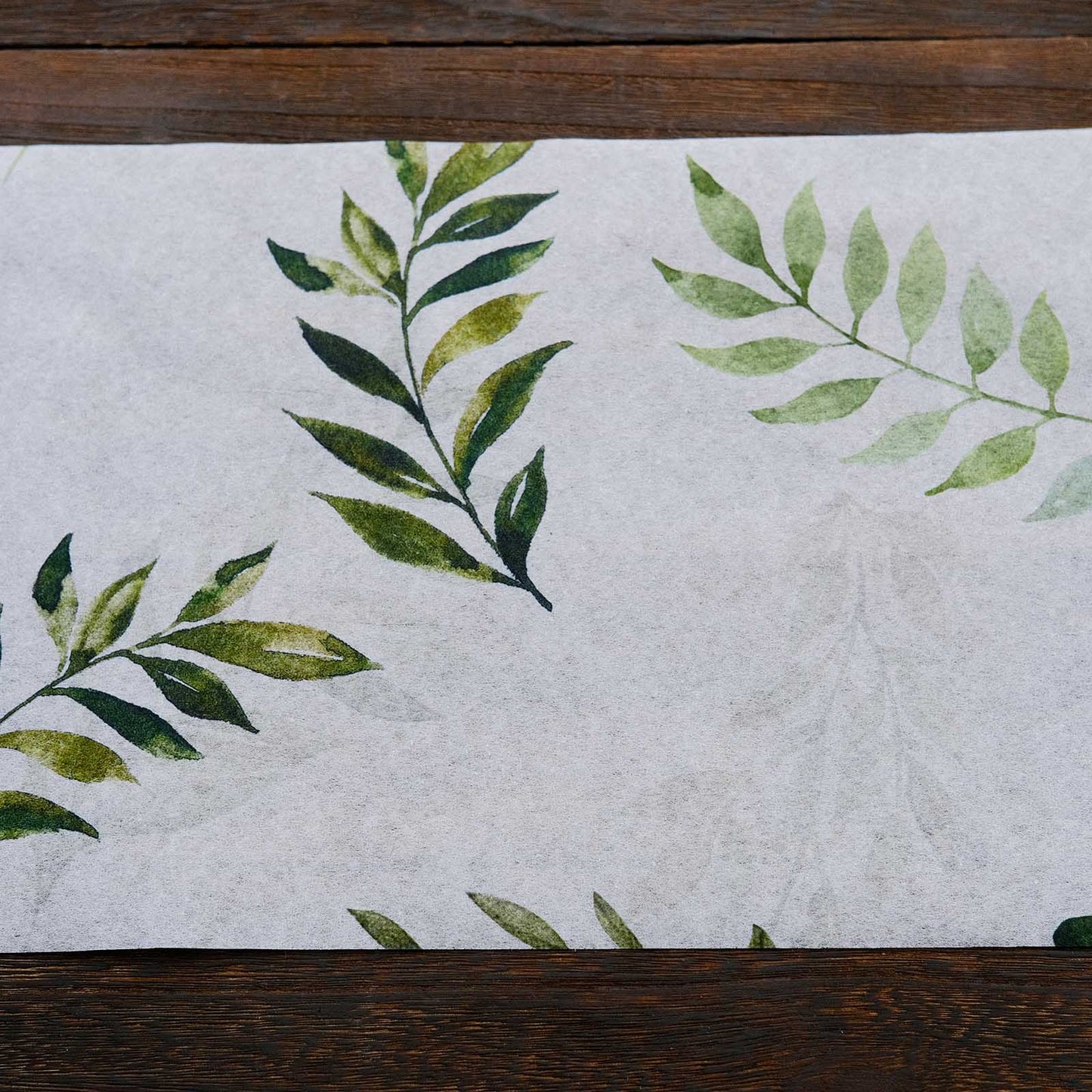 White table runner with green olive leaves print for stylish dining decor.
