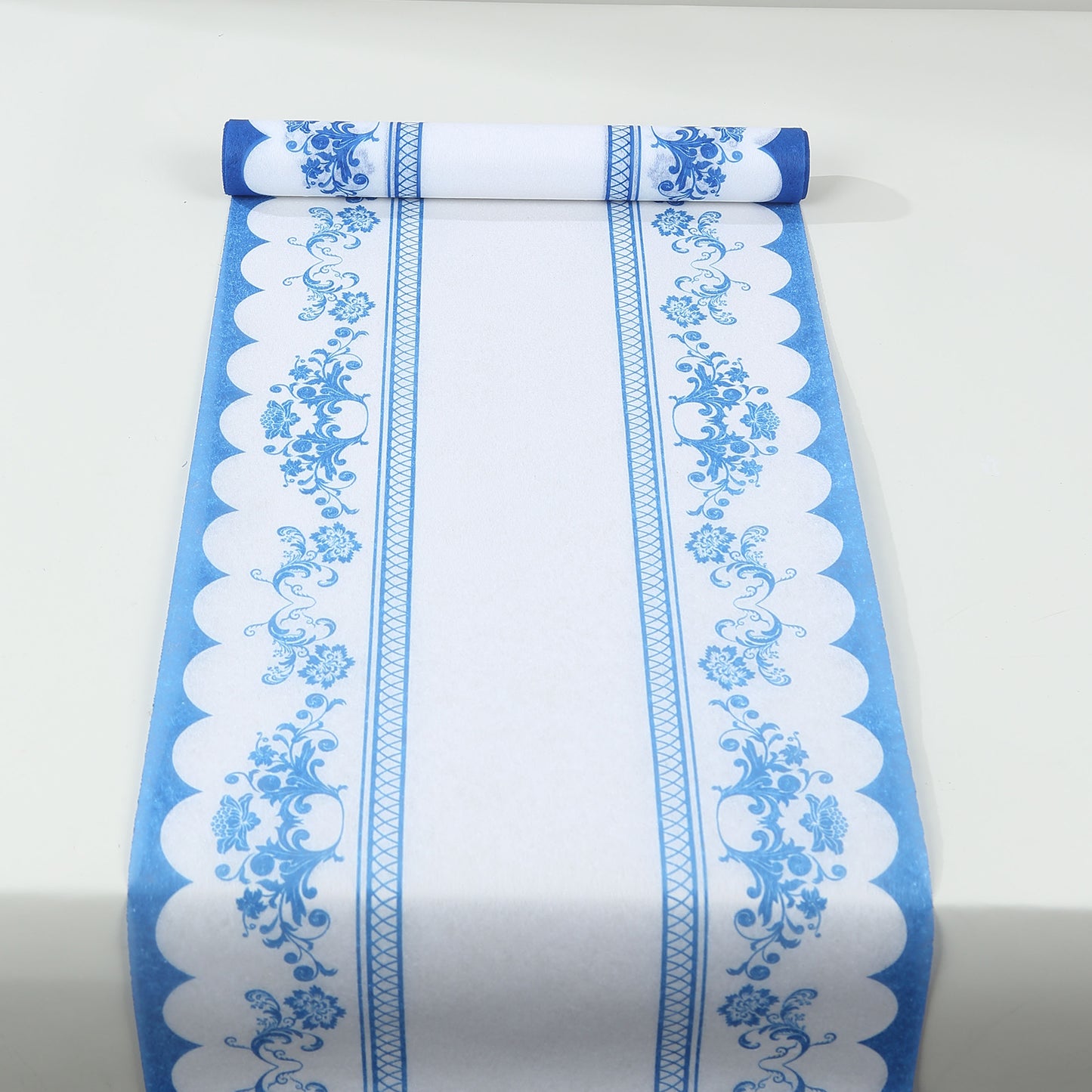 White disposable table runner with blue ornate floral prints.