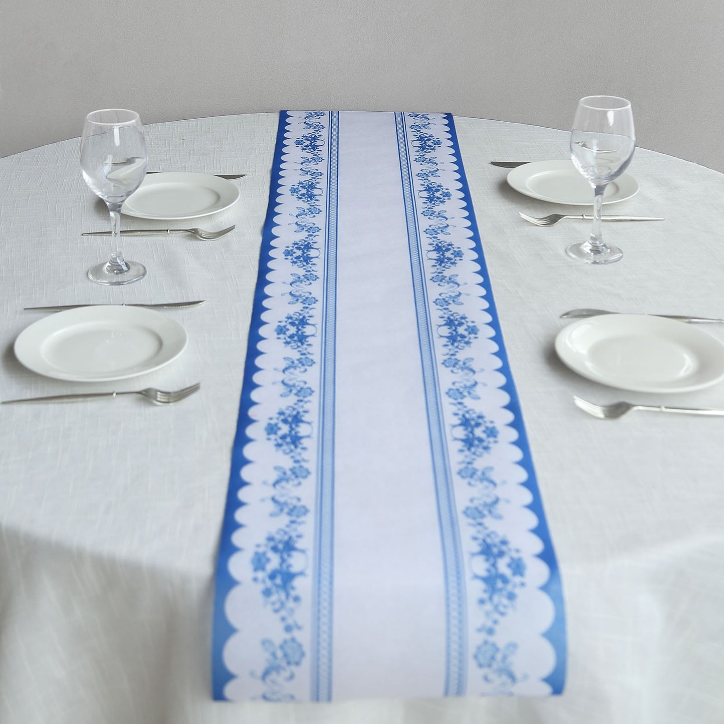 White table runner with blue ornate floral prints on a dining table setting.