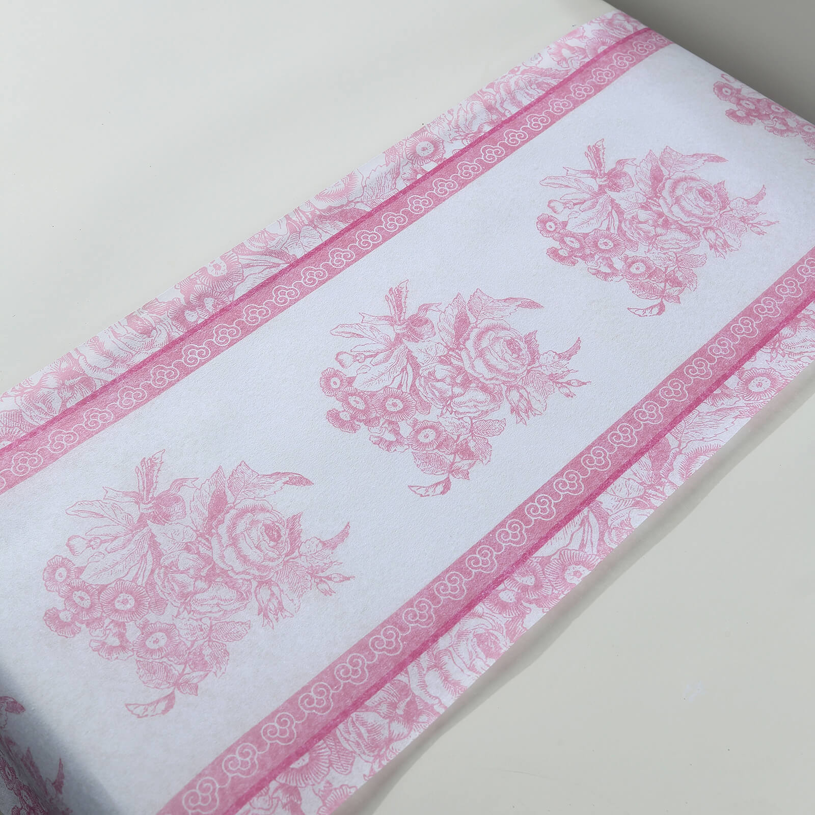 White table runner with pink floral pattern, perfect for stylish dining decor.