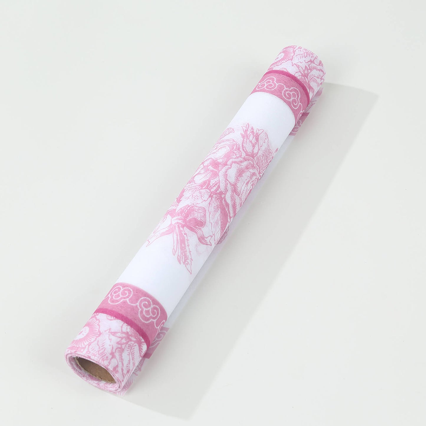 White with pink floral disposable table runner rolled up.
