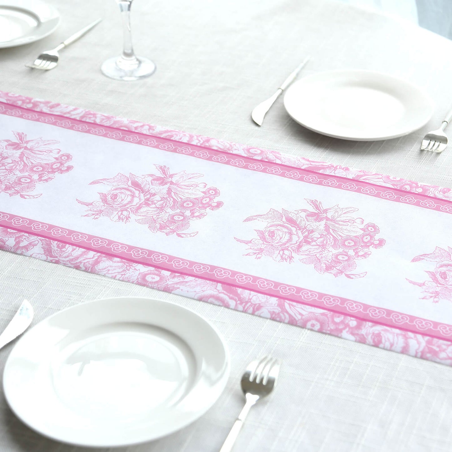 White table runner with pink floral pattern on a dining table setting.