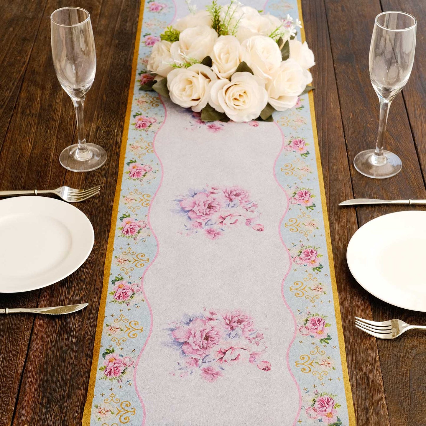 White disposable table runner with pink peony floral print on a wooden table setting.