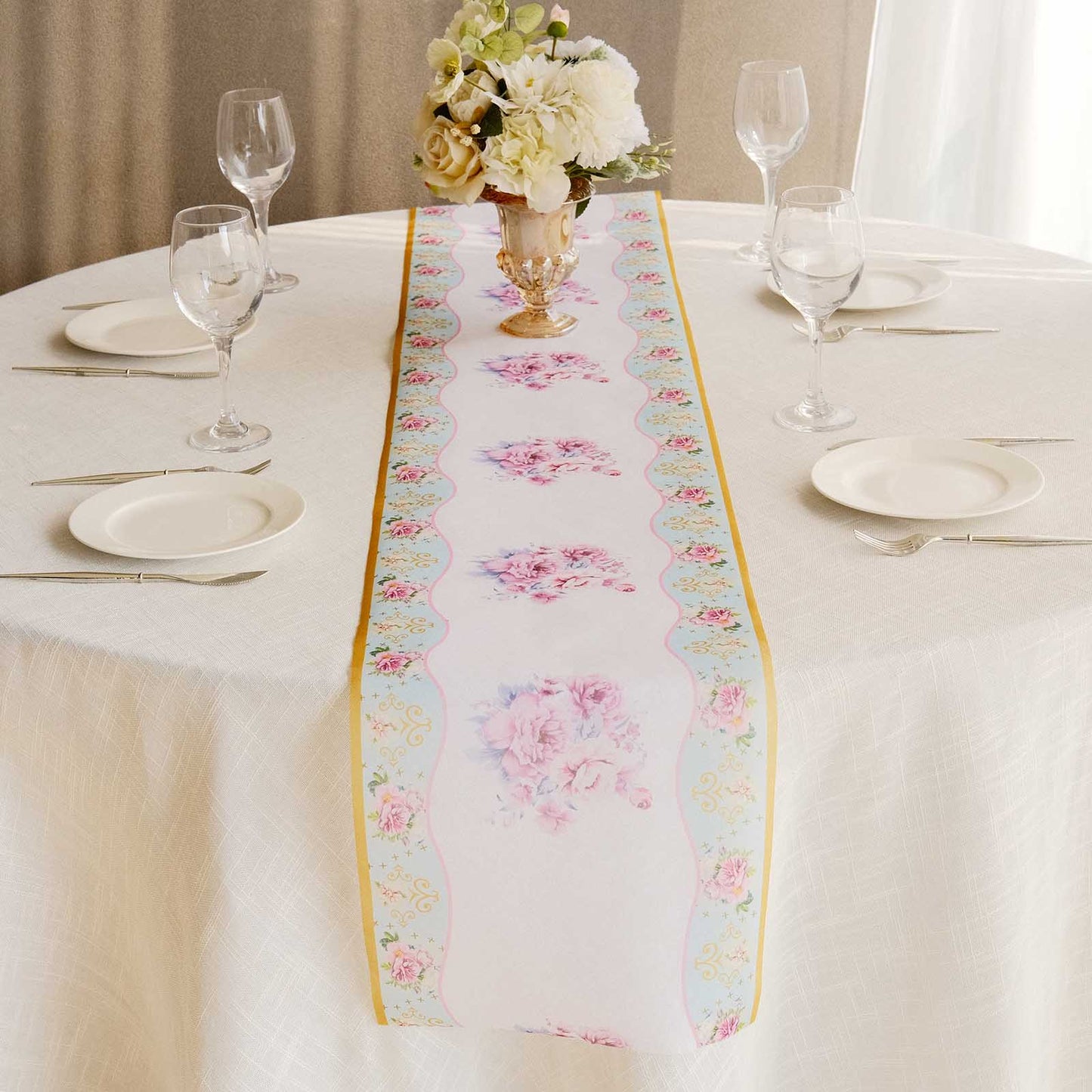 White table runner with pink peony floral print on a dining table setting.