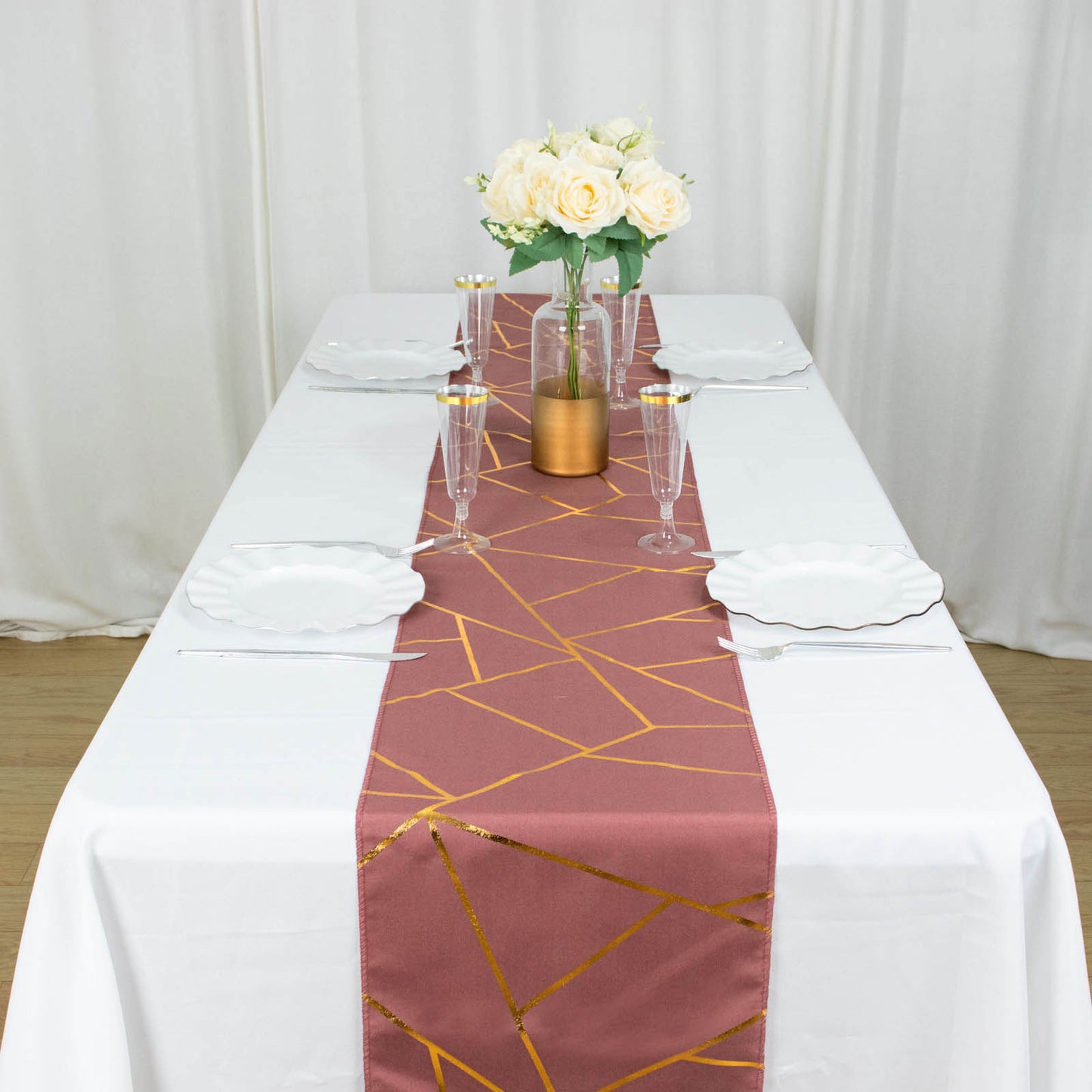 Cinnamon rose table runner with gold geometric pattern on a white table.