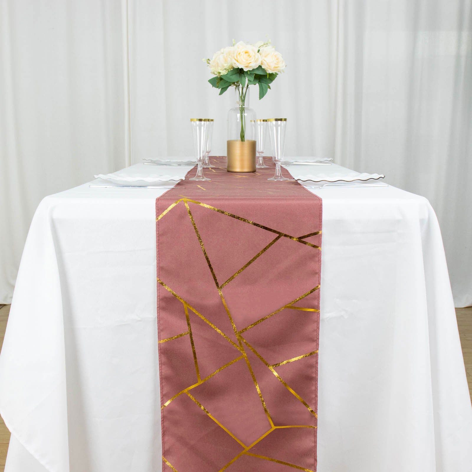 Cinnamon rose table runner with gold foil geometric pattern on a white table.