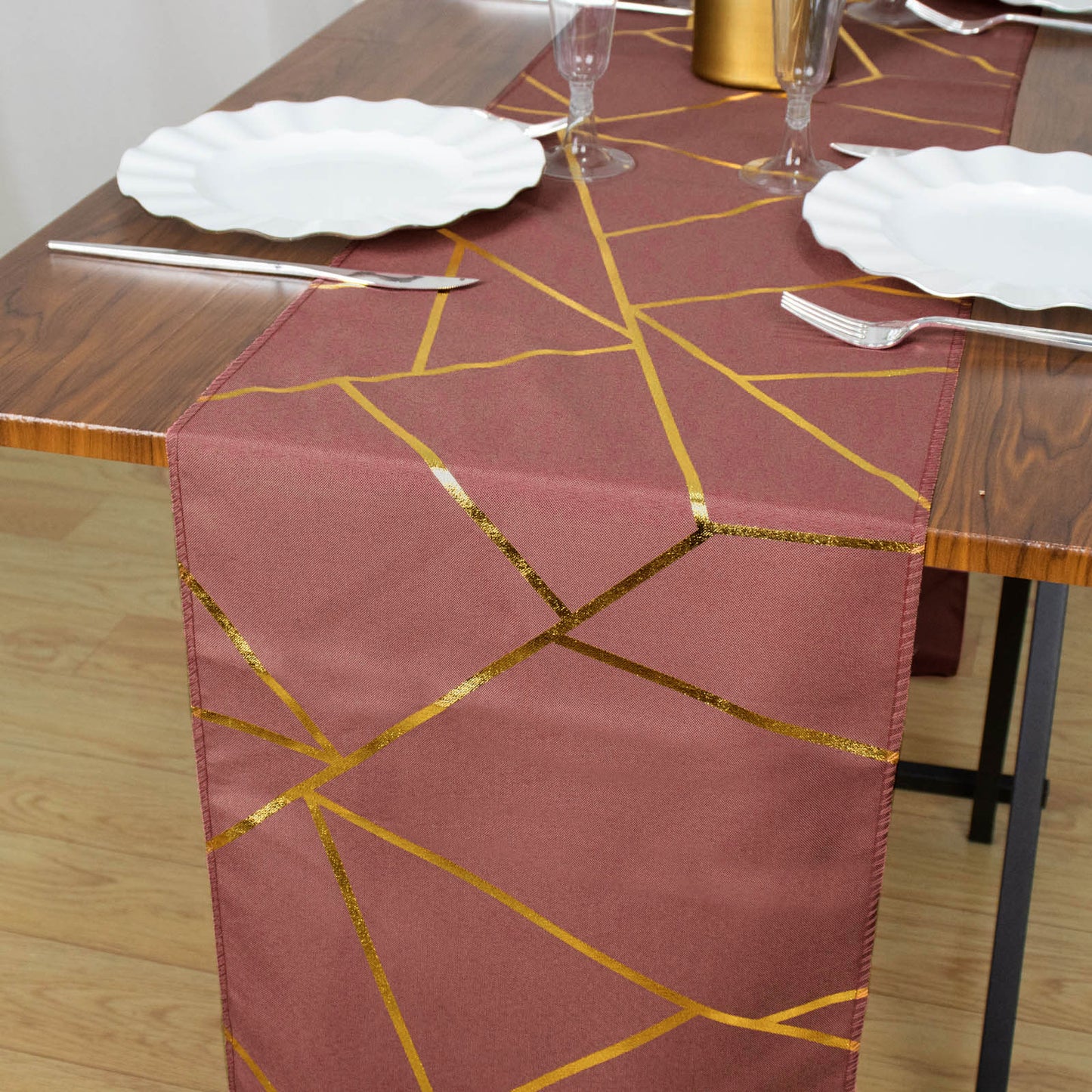 Cinnamon rose table runner with gold foil geometric pattern on a wooden table.