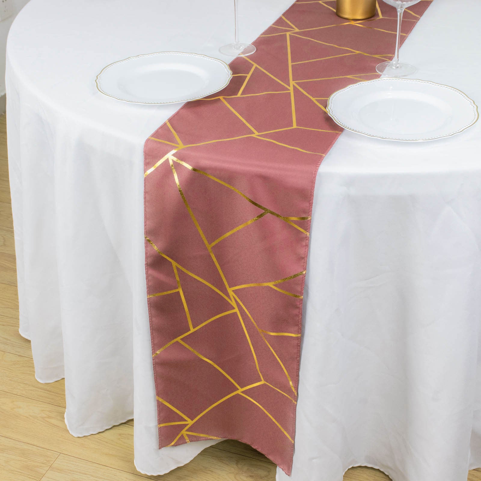 Cinnamon rose table runner with gold foil geometric pattern on a white table.