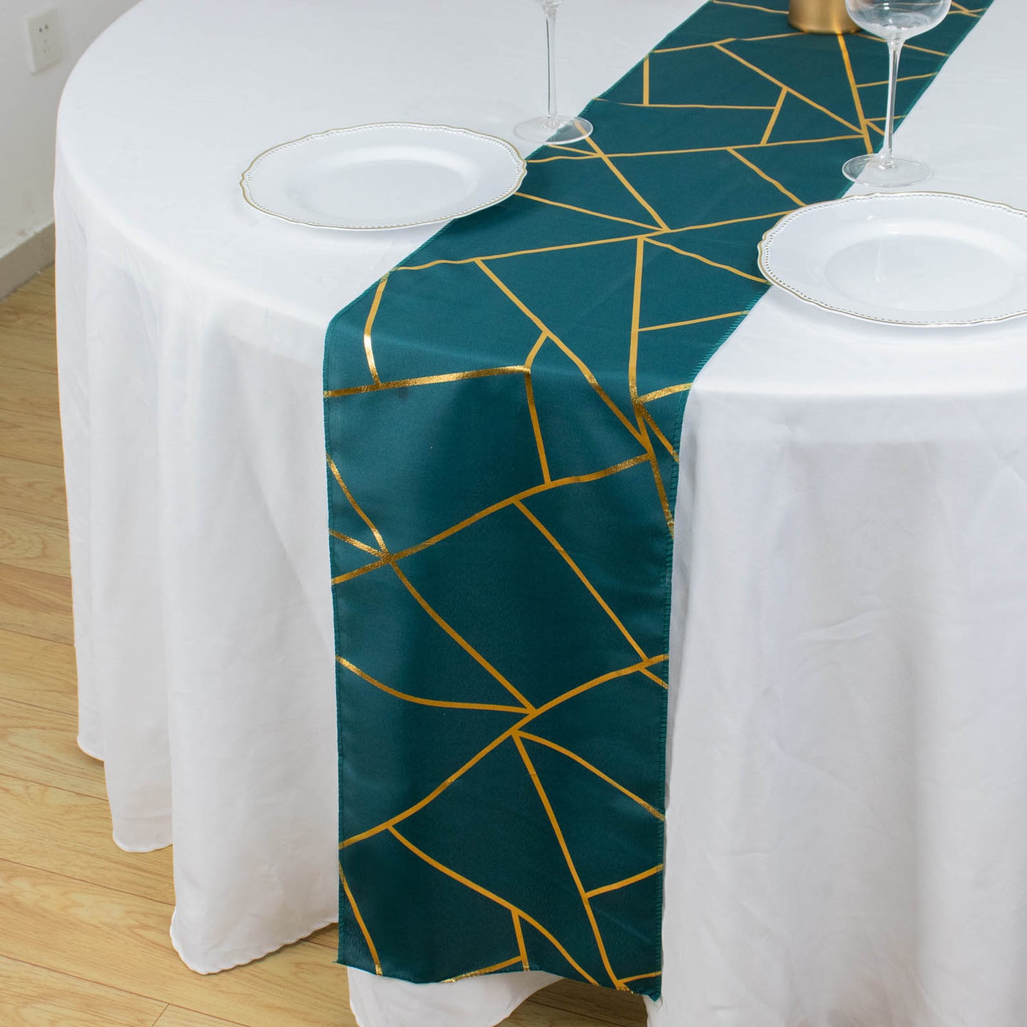 Peacock teal table runner with gold foil geometric pattern on a white table.
