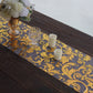Metallic gold sheer organza table runner with swirl foil flower design.