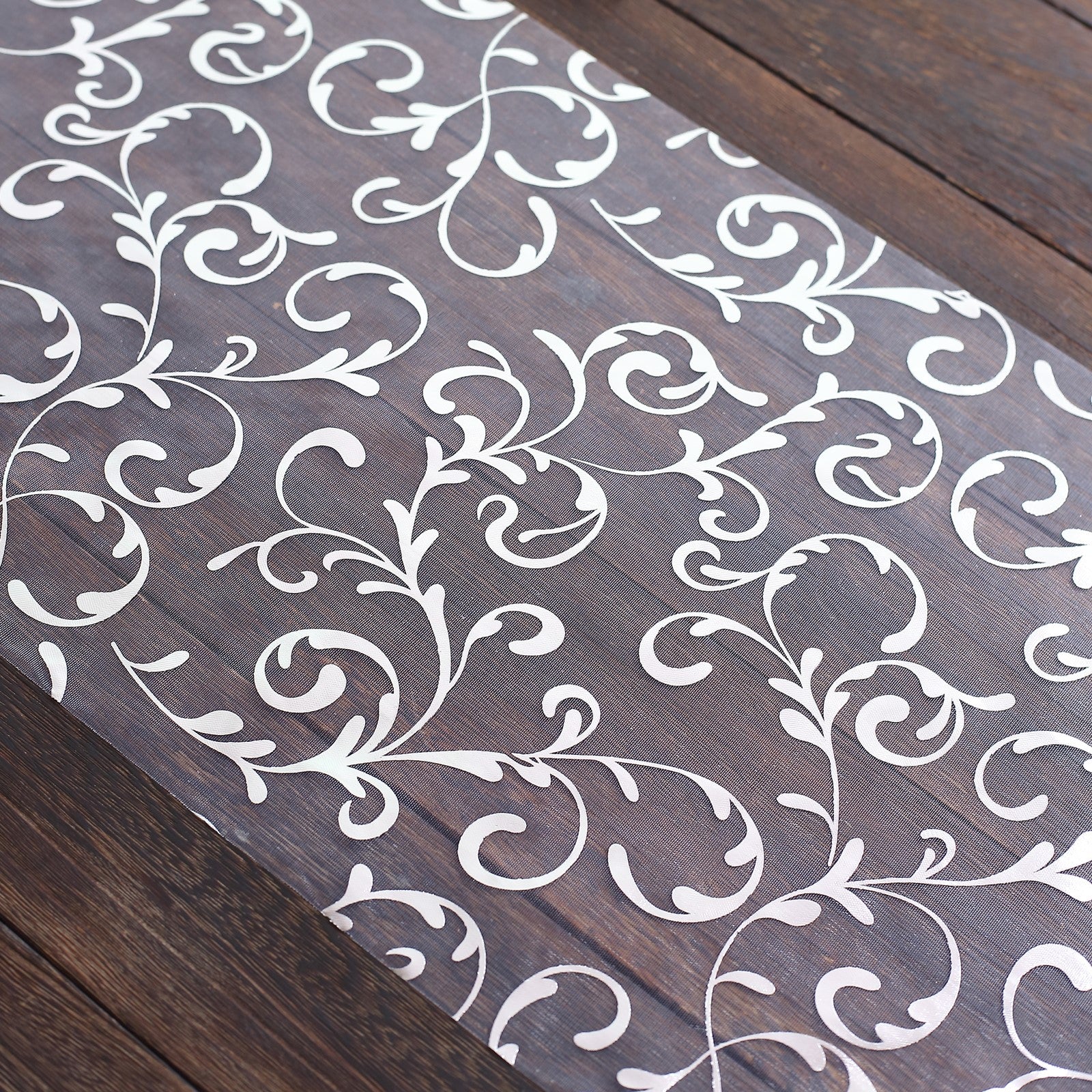 Metallic silver mesh table runner with embossed foil flower design.