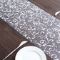 Metallic silver mesh table runner with embossed foil flower design.