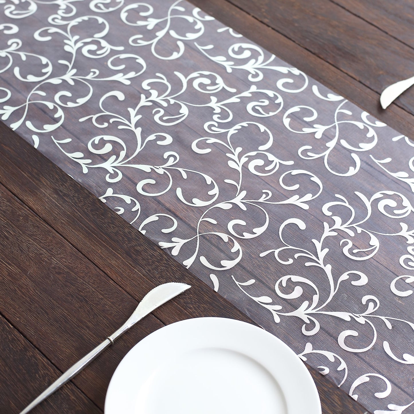 Metallic silver mesh table runner with embossed foil flower design.