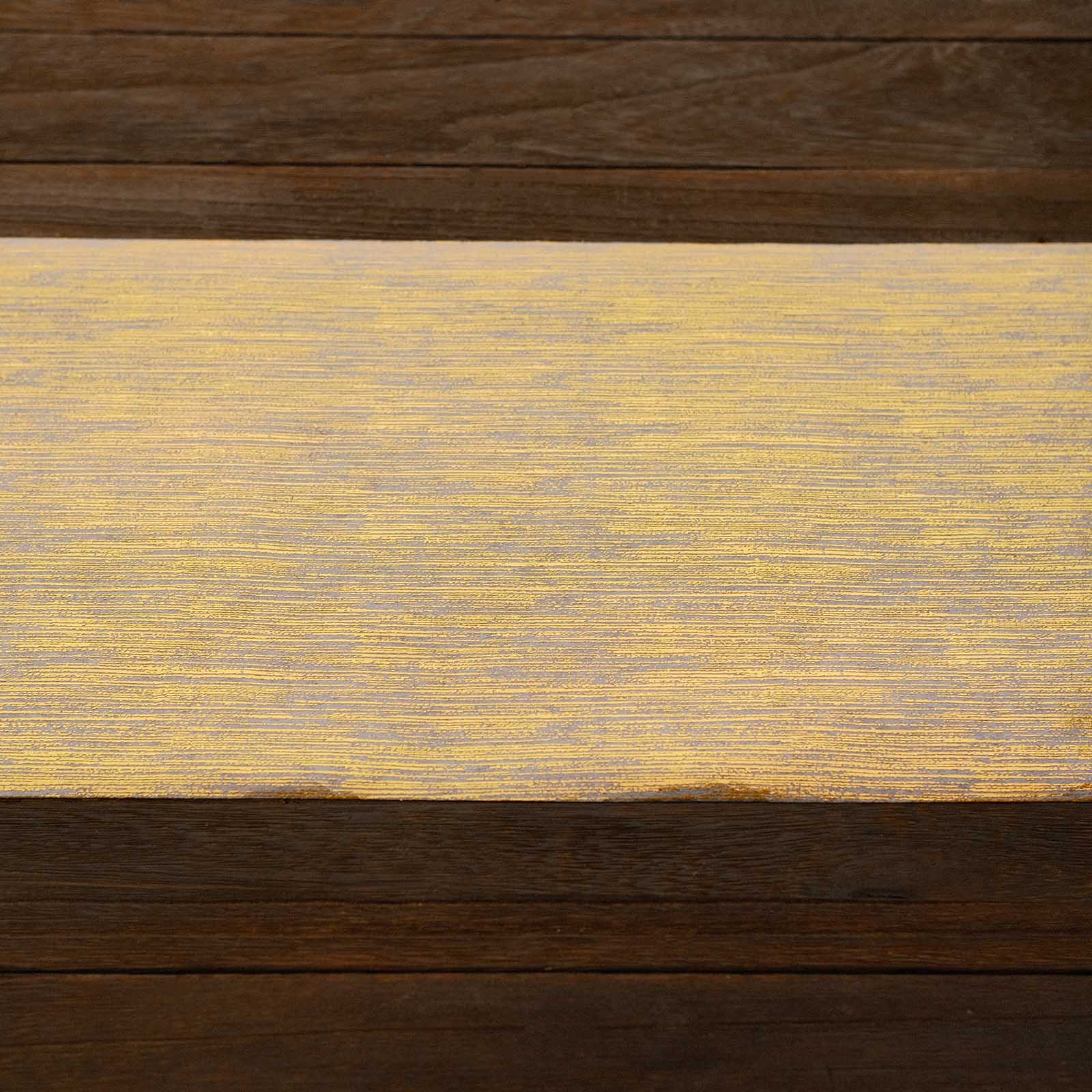 Metallic gold faux suede table runner roll on a wooden surface.