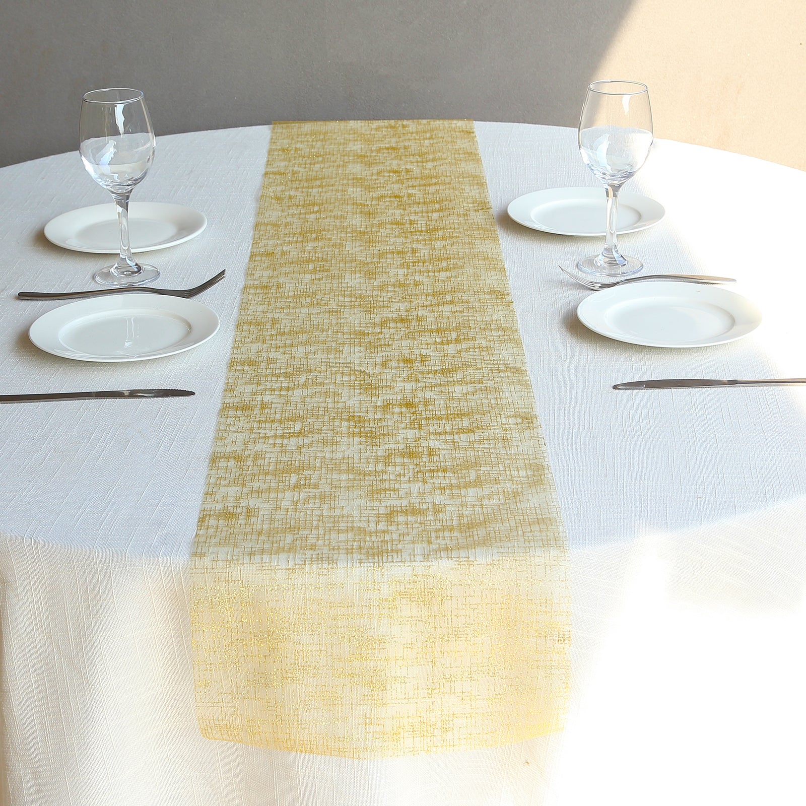 Metallic gold glitter mesh polyester disposable table runner on a round table.