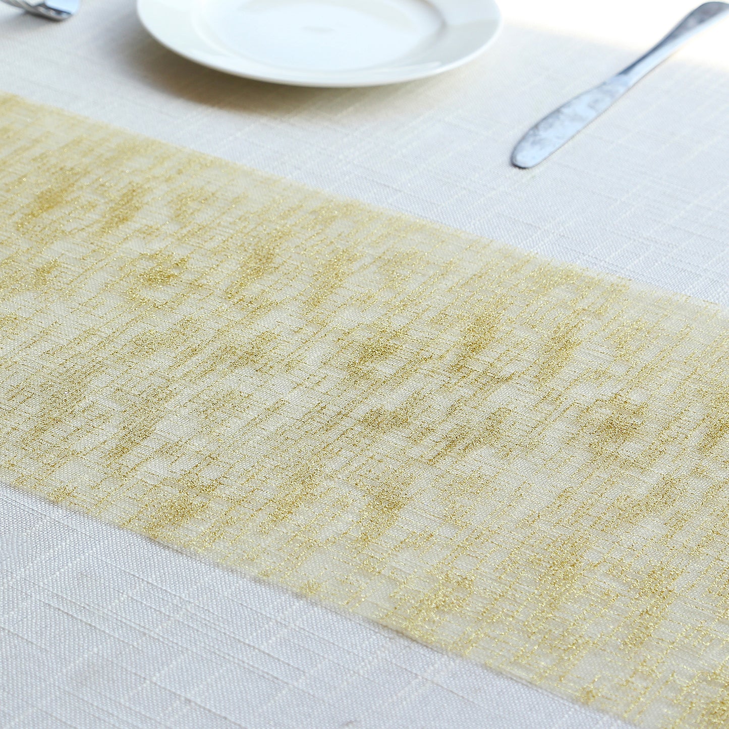 Metallic gold glitter mesh table runner on a light table setting.