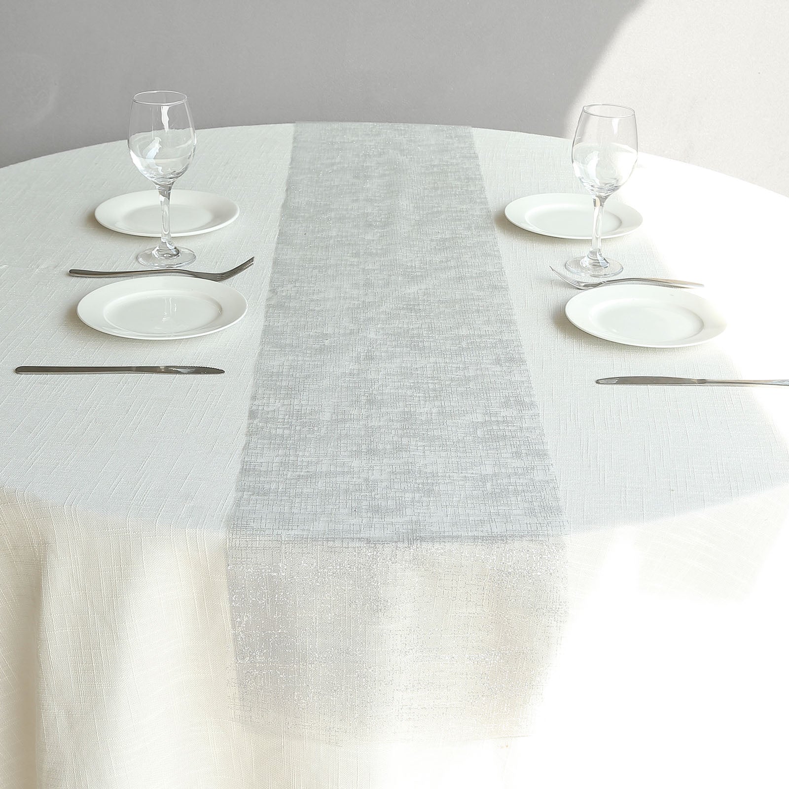 Metallic silver glitter disposable table runner on a round table setting.