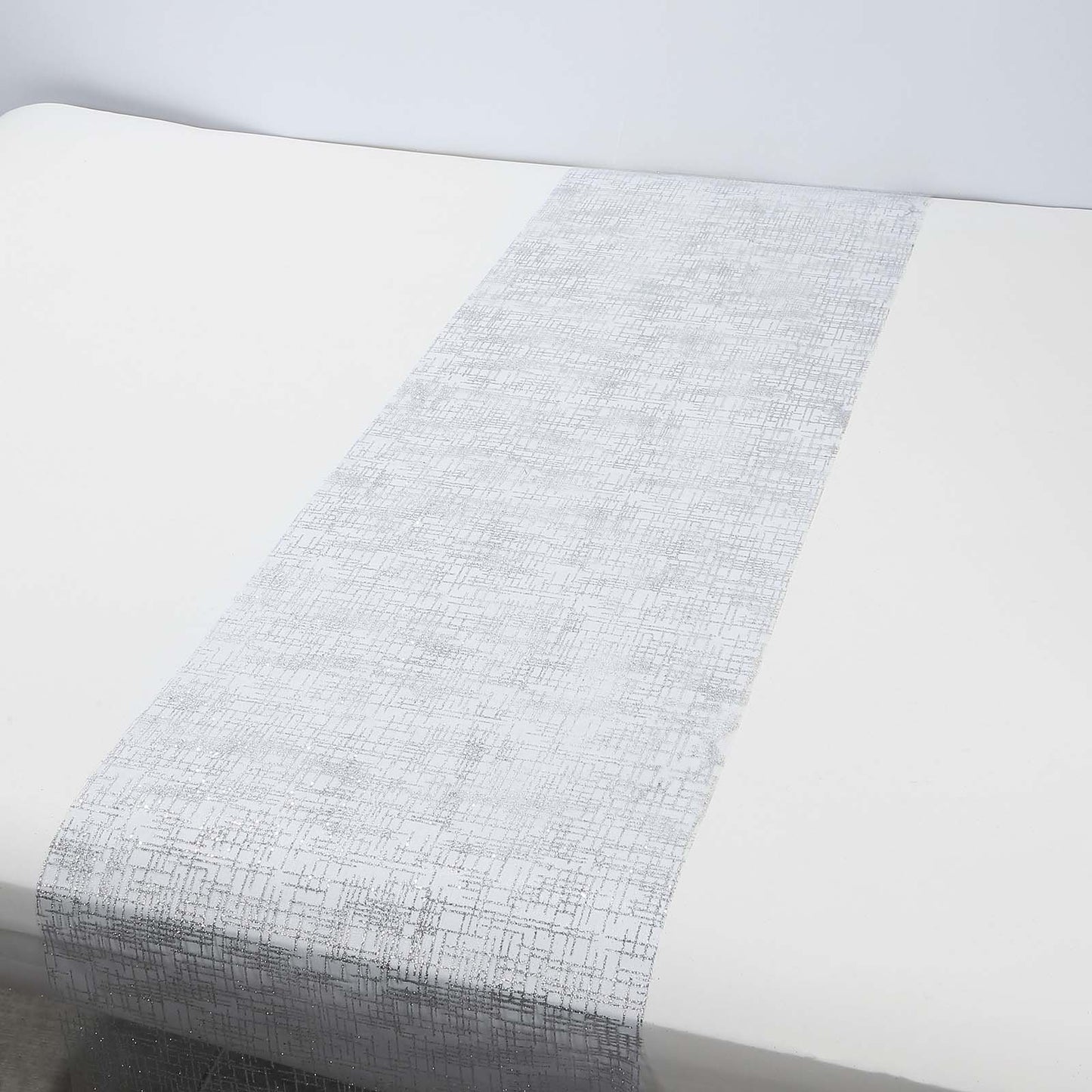Metallic silver glitter mesh table runner on a white table.