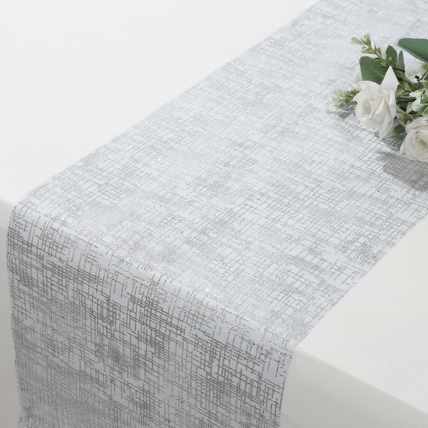 Metallic silver glitter mesh disposable table runner on a white table.