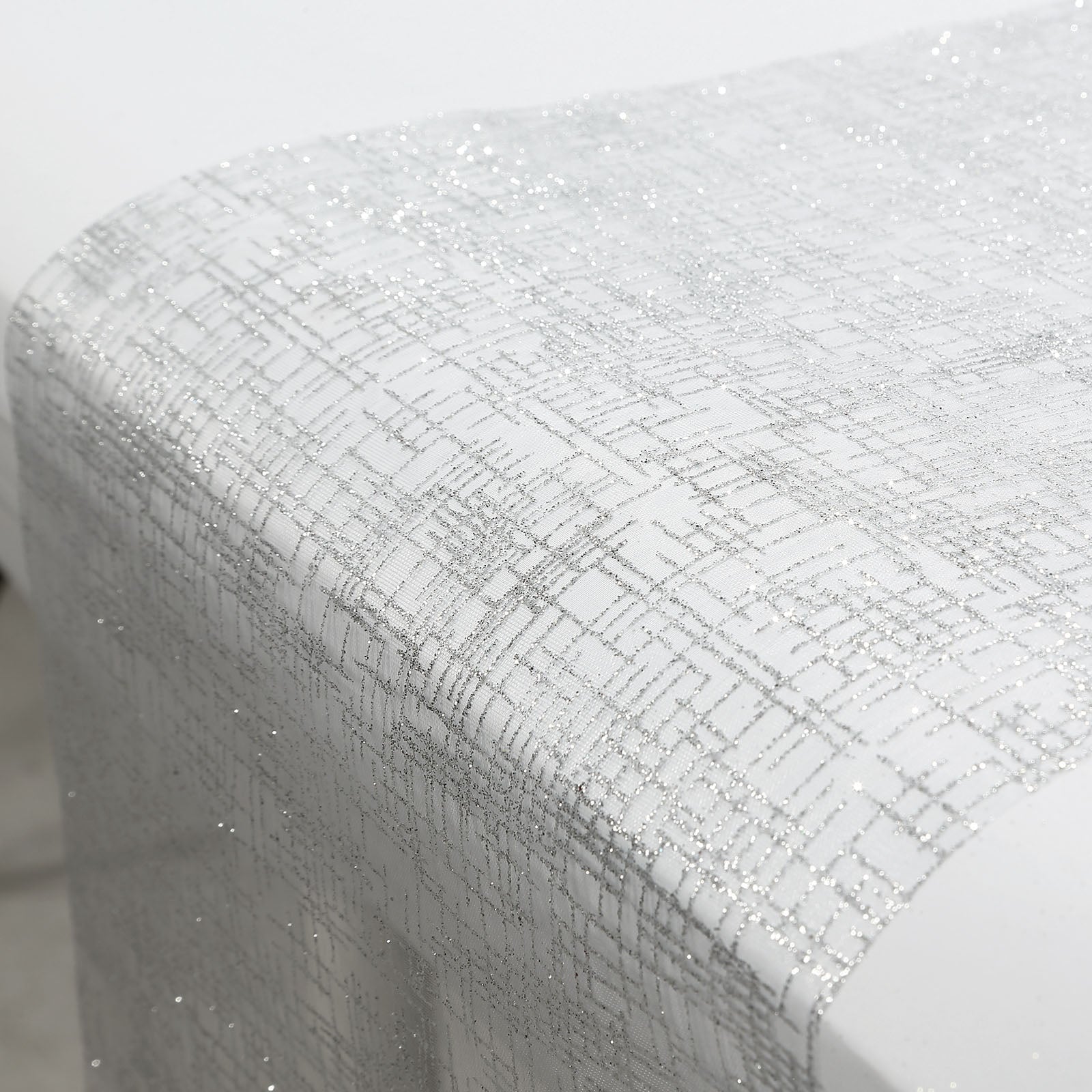 Metallic silver glitter mesh polyester disposable table runner on a white table.