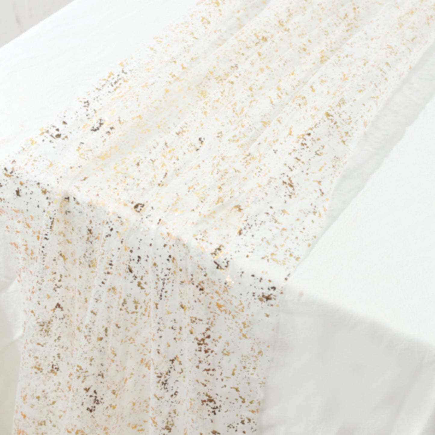 Metallic gold glitter sheer chiffon table runner on a white table.