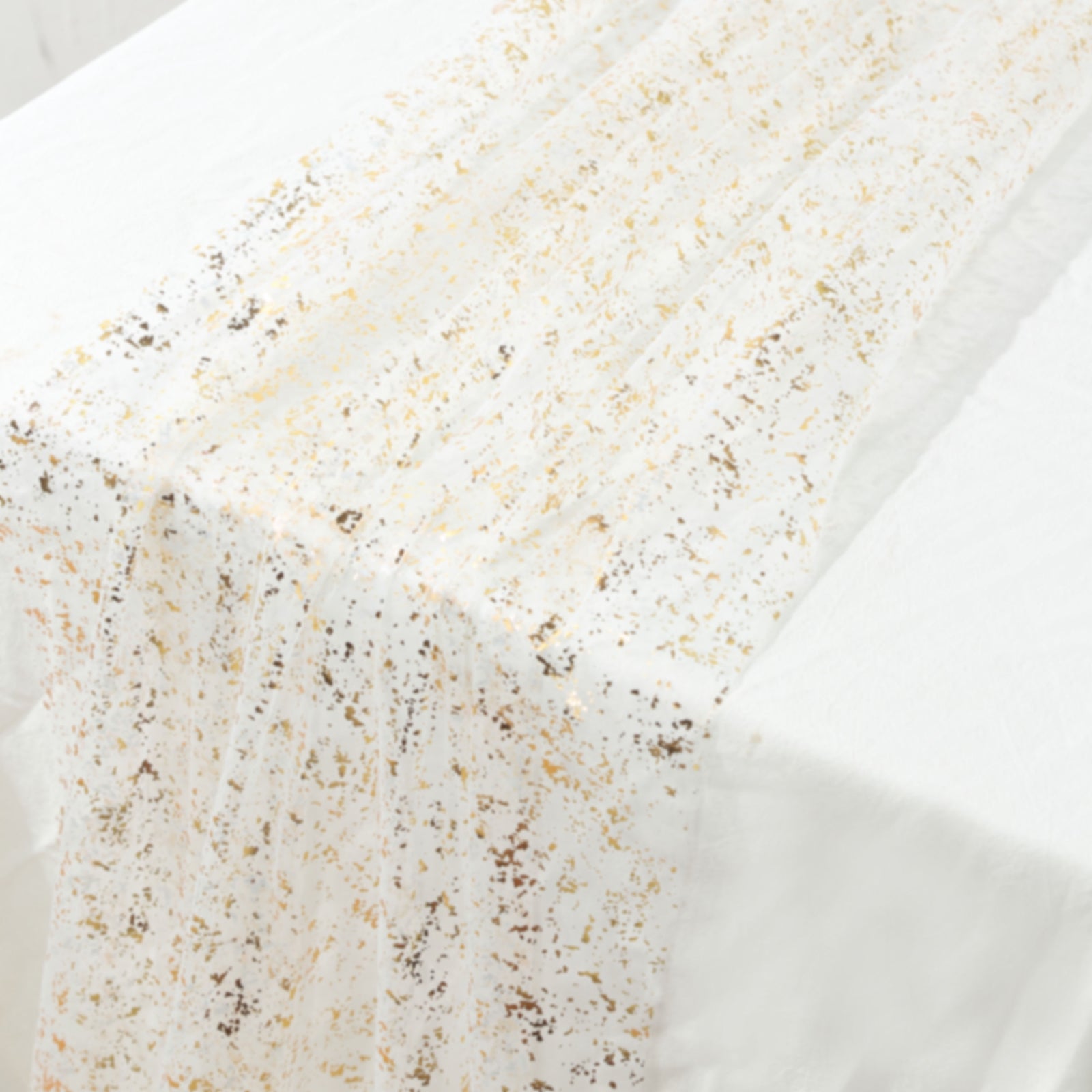 Metallic gold glitter sheer chiffon table runner on a white table.
