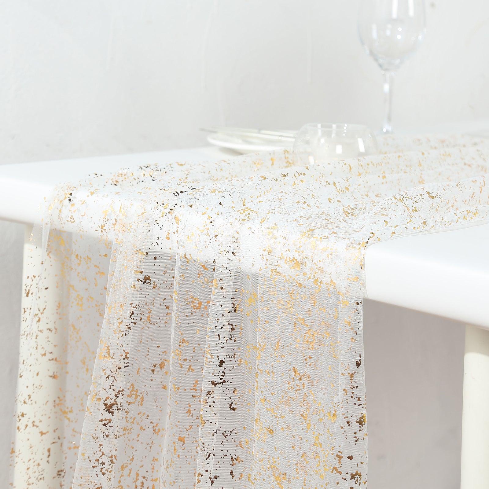 Metallic gold glitter sheer chiffon table runner on a white table.