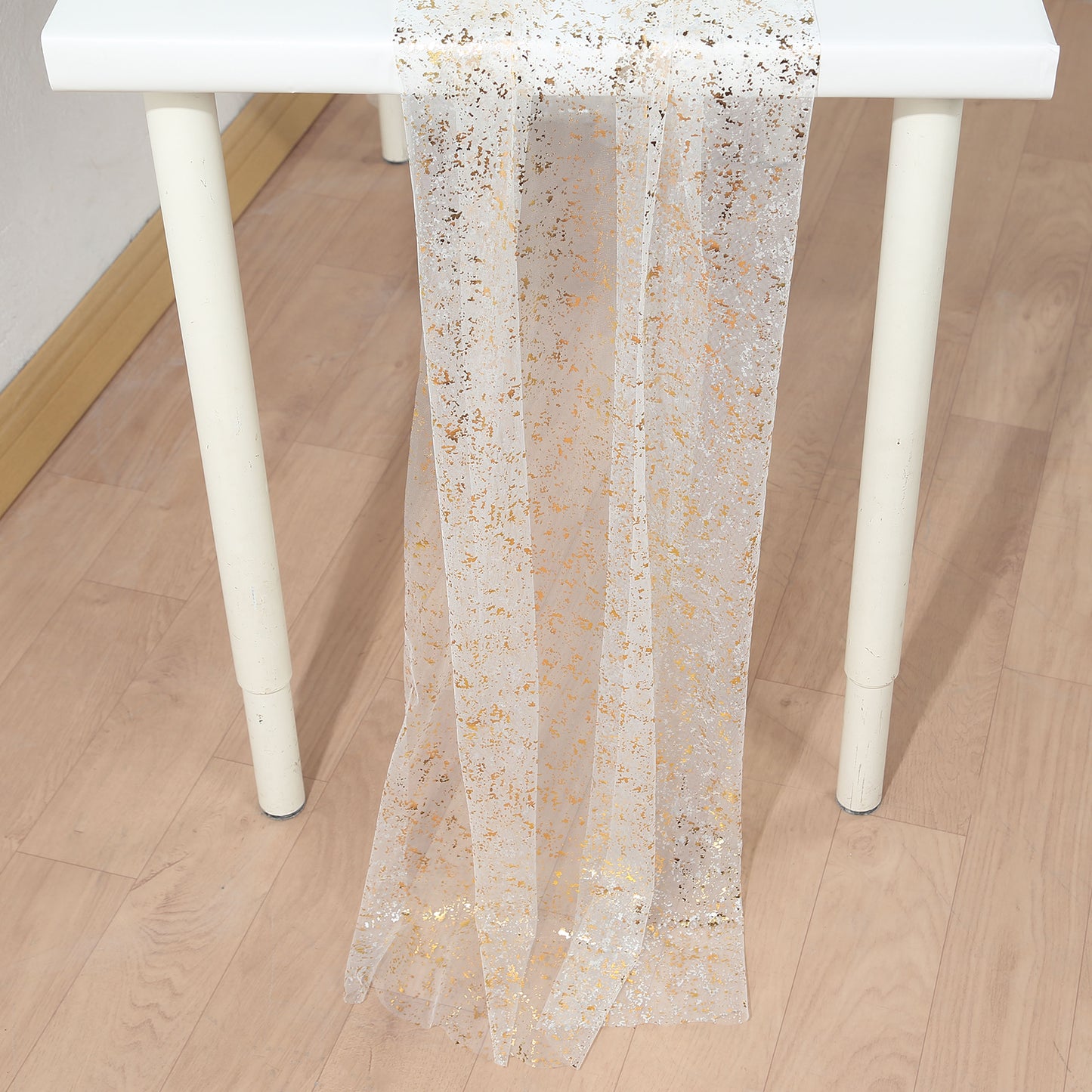 Metallic gold glitter sheer chiffon table runner on a white table.
