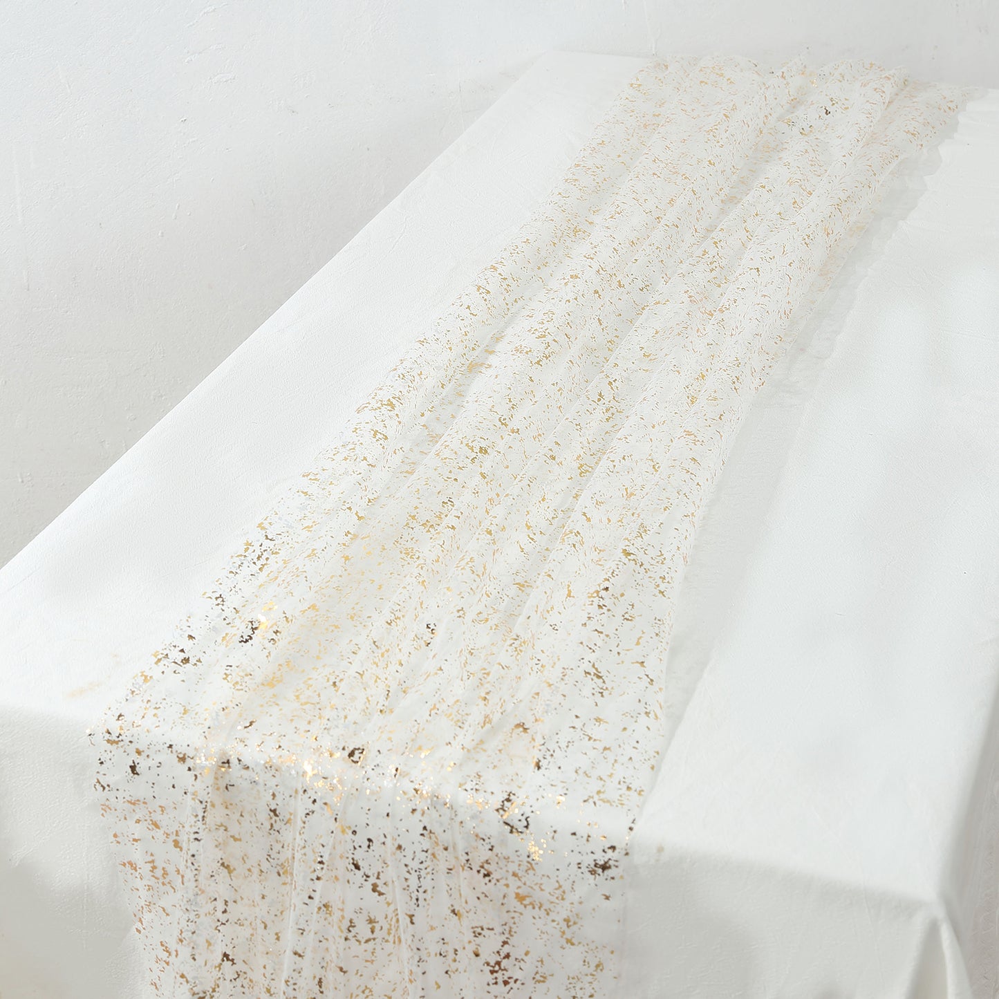 Metallic gold glitter sheer chiffon table runner on a white table.