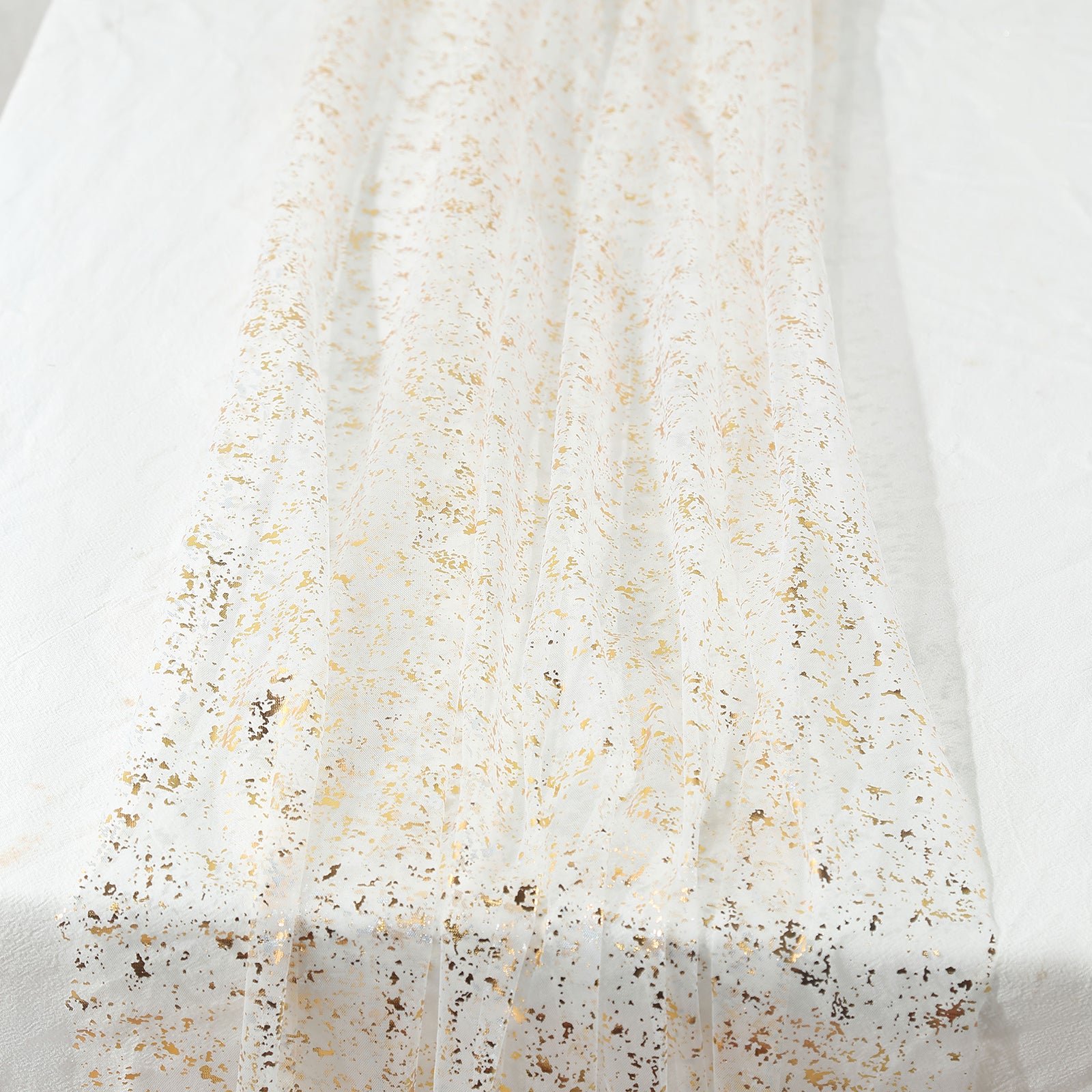 Metallic gold glitter sheer chiffon table runner on a white surface.