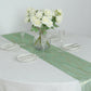 Emerald green mesh organza table runner with gold wave pattern on a dining table.