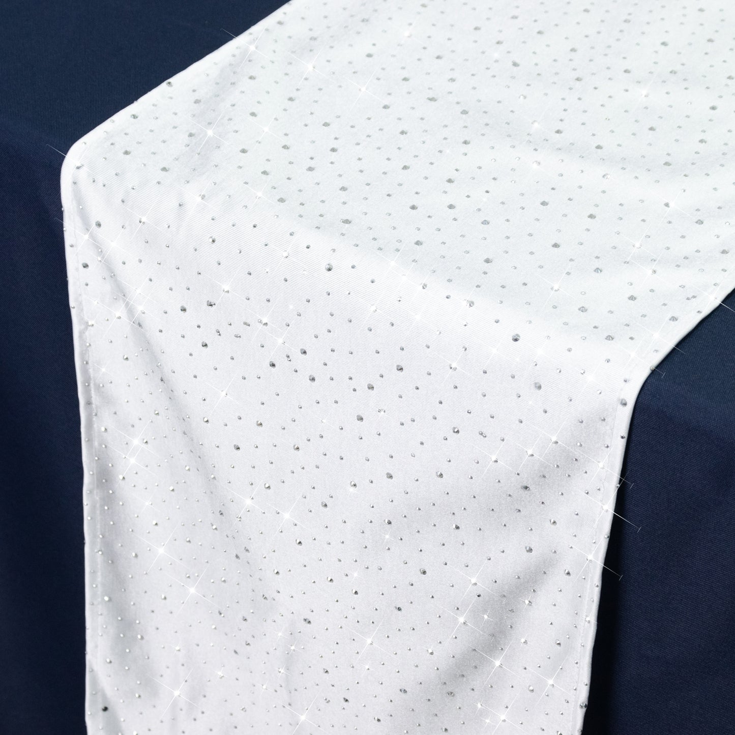 White table runner with rhinestone accents on a dark table.