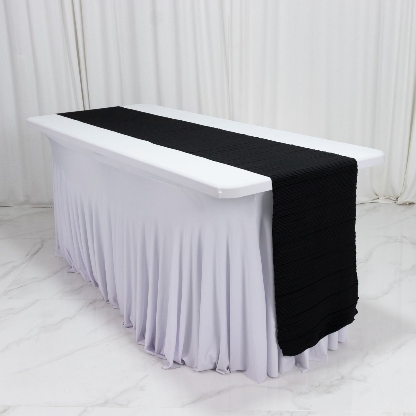 Black accordion pleated table runner on a white table.