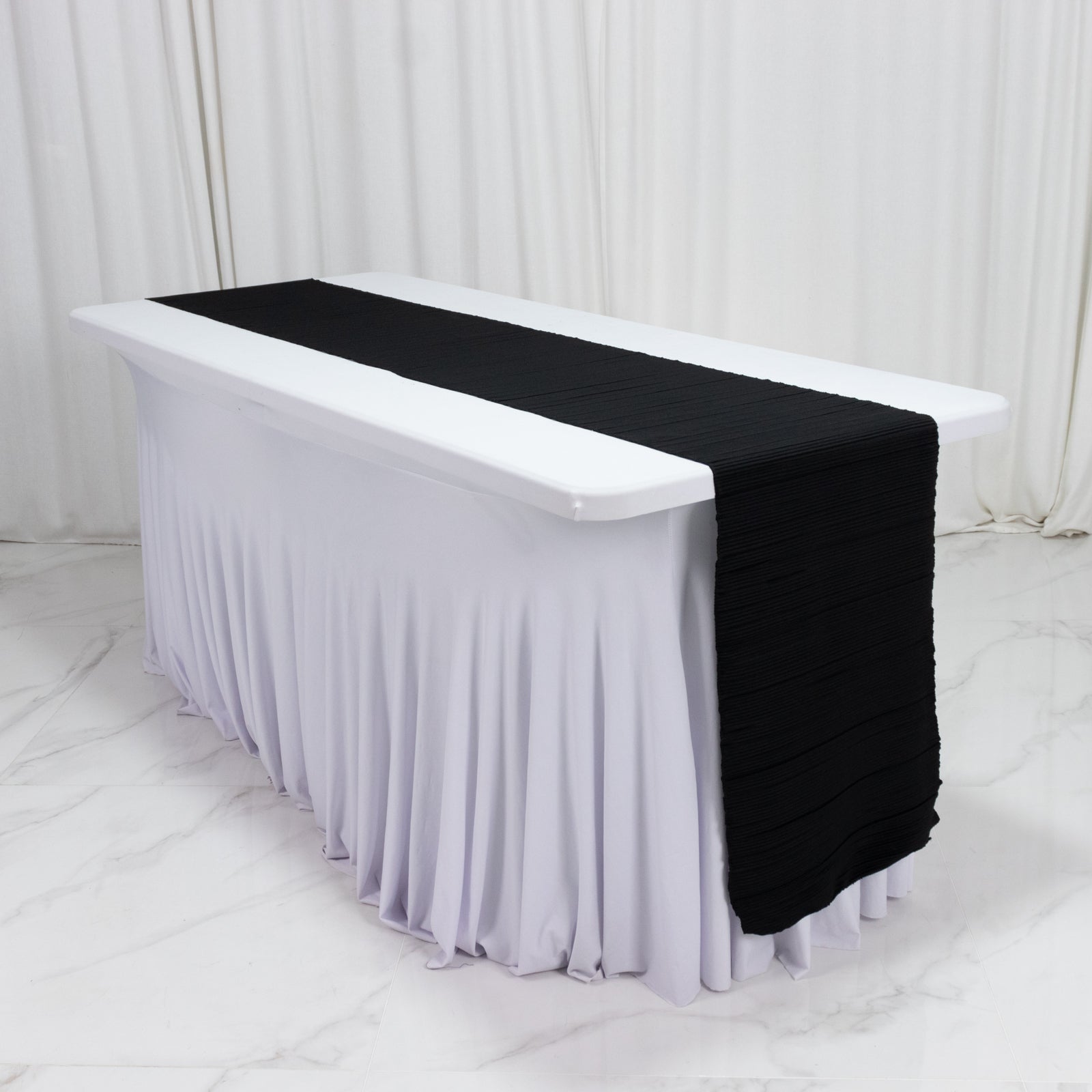 Black accordion pleated table runner on a white table.