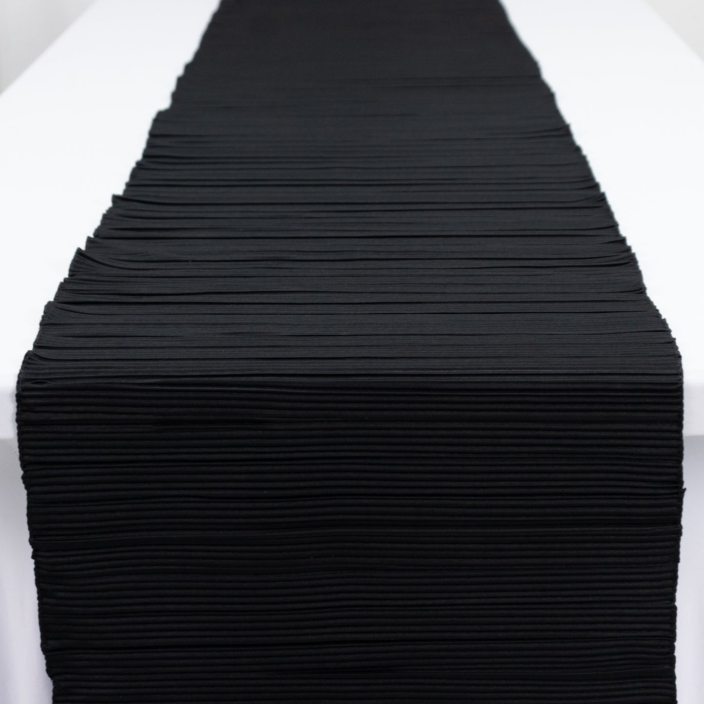Black accordion pleated table runner, 12" x 108", wrinkle-free and stain-resistant.