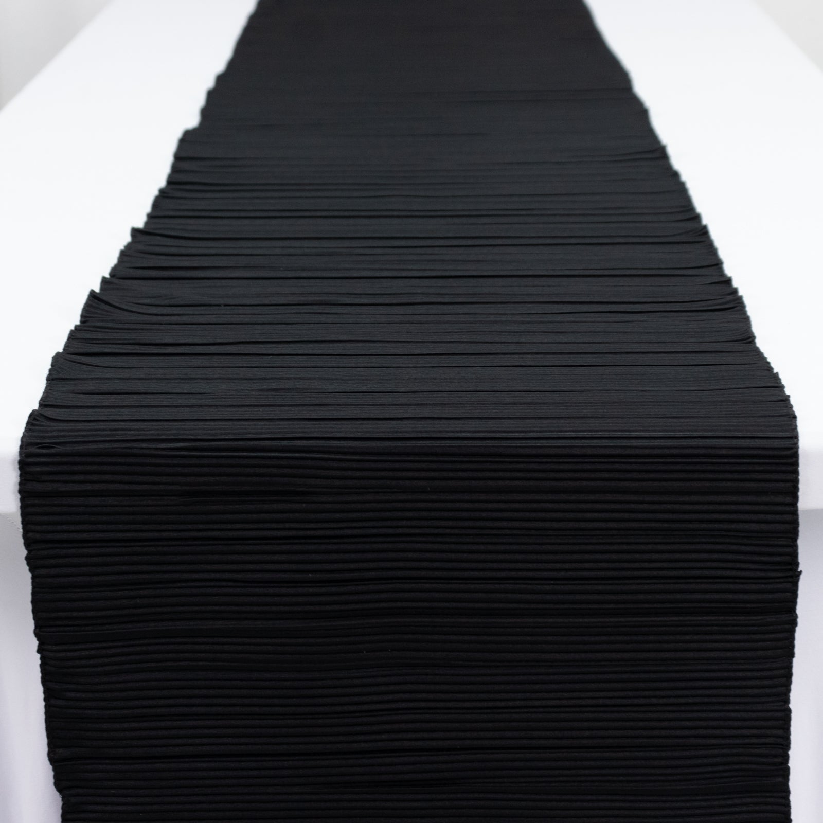Black accordion pleated table runner, 12" x 108", wrinkle-free and stain-resistant.