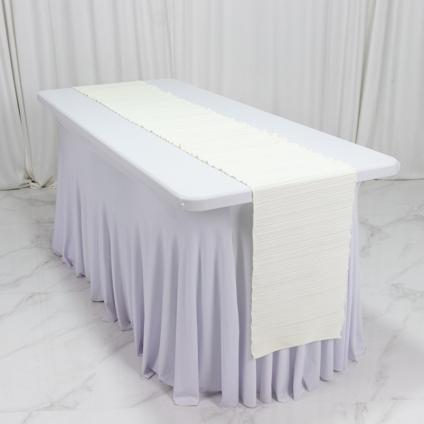 Ivory accordion pleated scuba table runner on a white table.