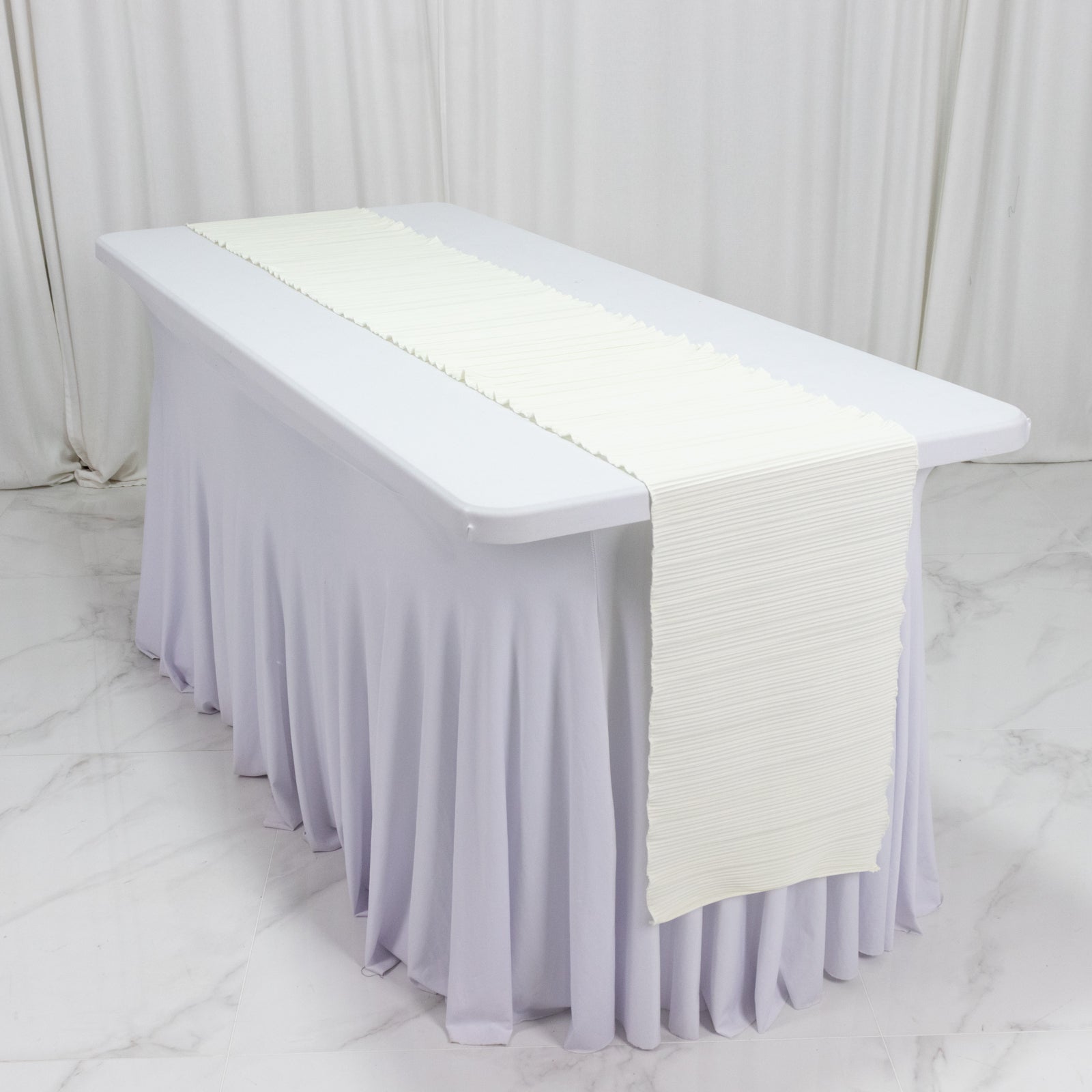 Ivory accordion pleated scuba table runner on a white table.