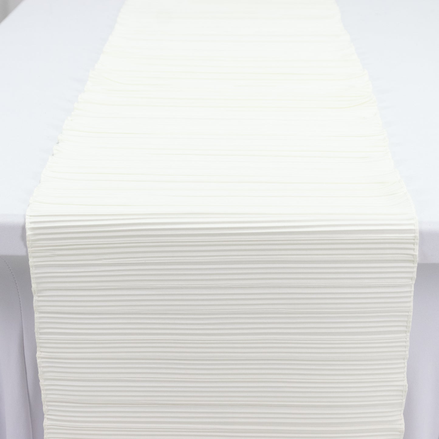 Ivory accordion pleated scuba table runner, wrinkle-free and stain-resistant.