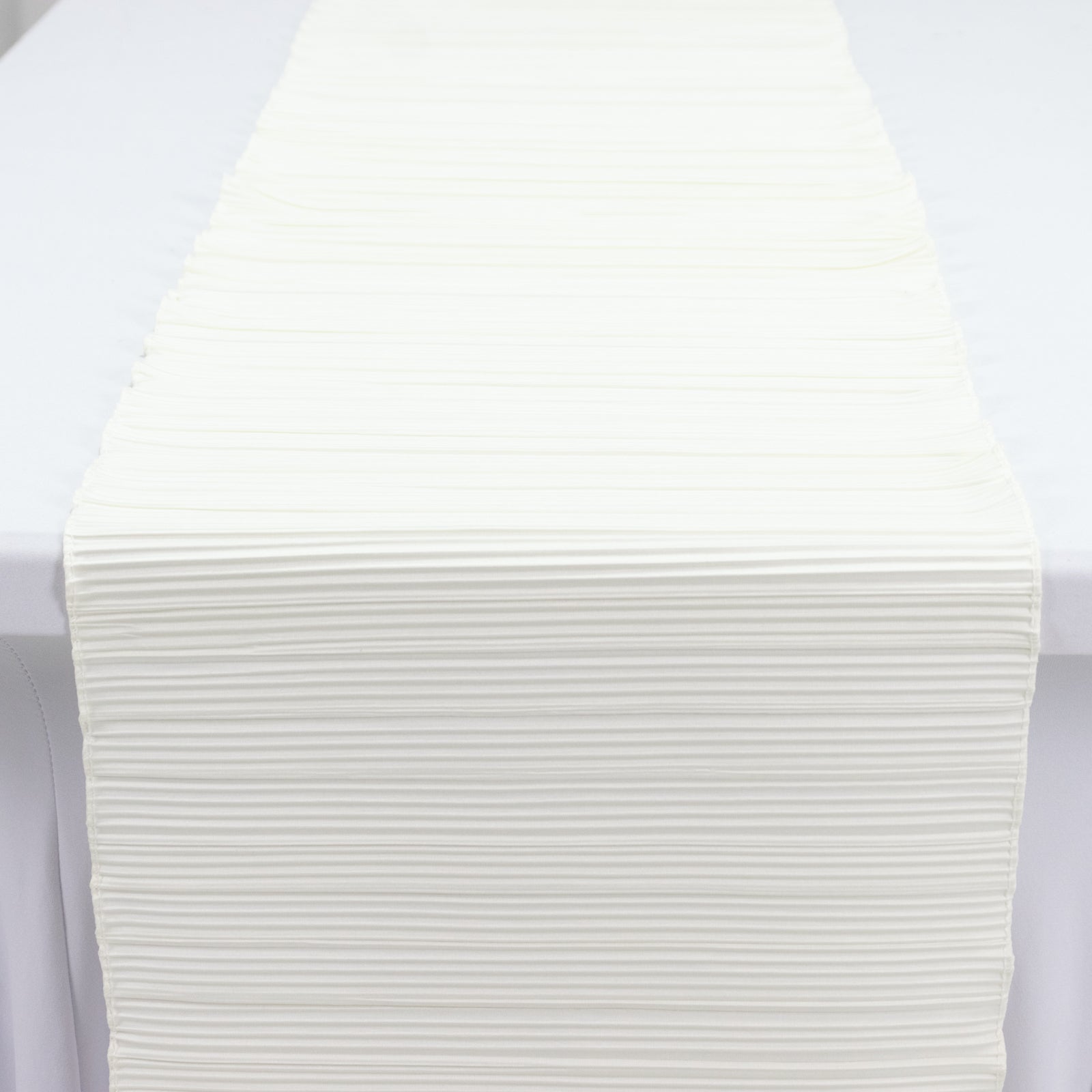 Ivory accordion pleated scuba table runner, wrinkle-free and stain-resistant.