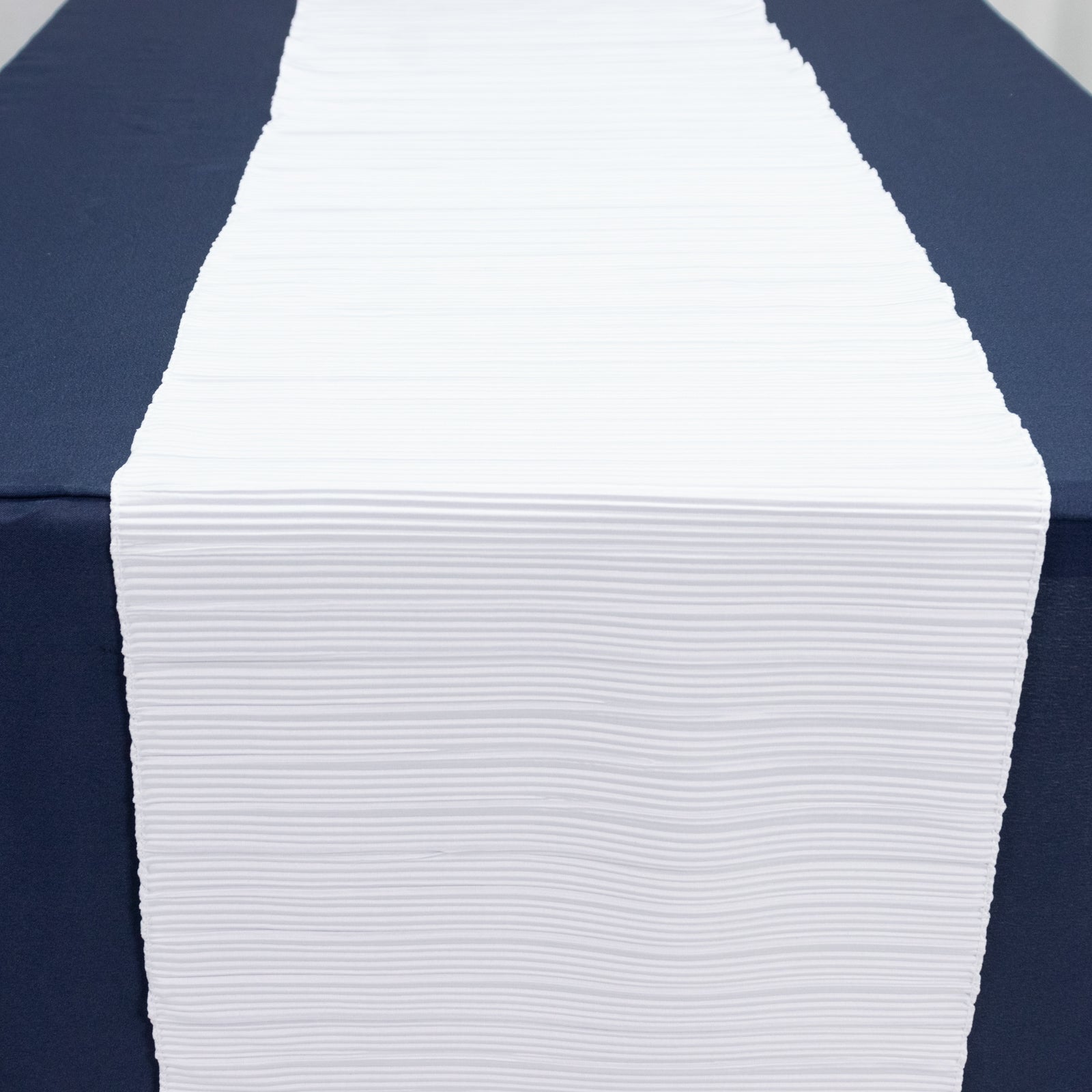 White accordion pleated table runner on a navy blue table.
