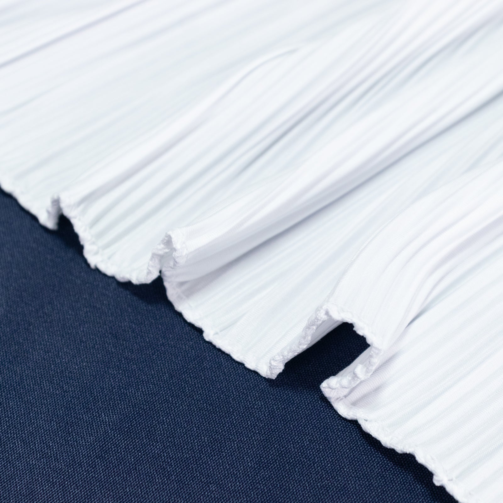 White accordion pleated table runner on a dark blue table.